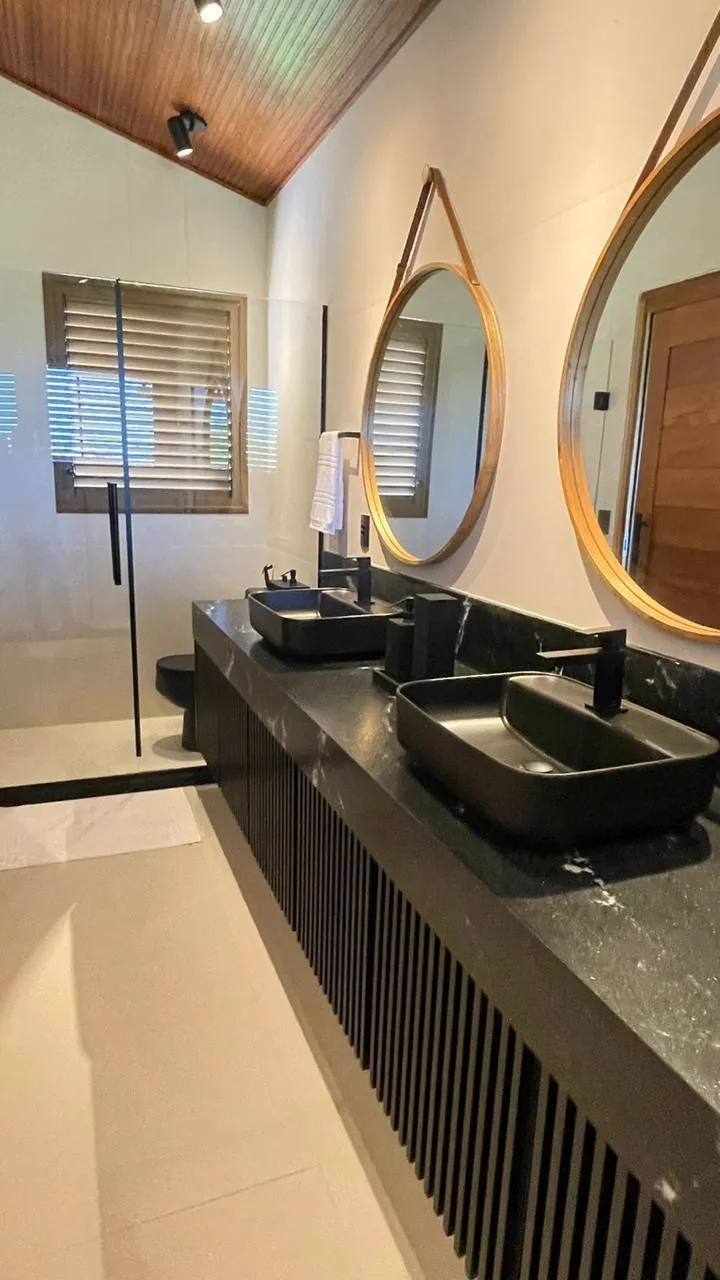 Banheiro com cubas duplas, espelhos redondos e ducha